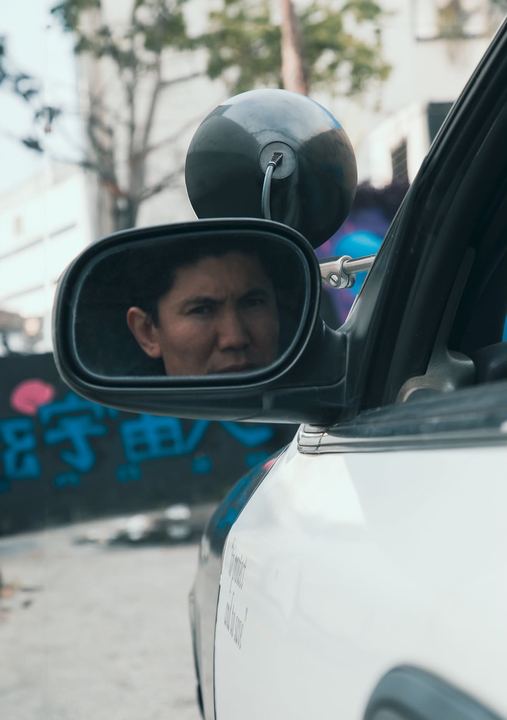 Medet's face reflected in a patrol car side mirror